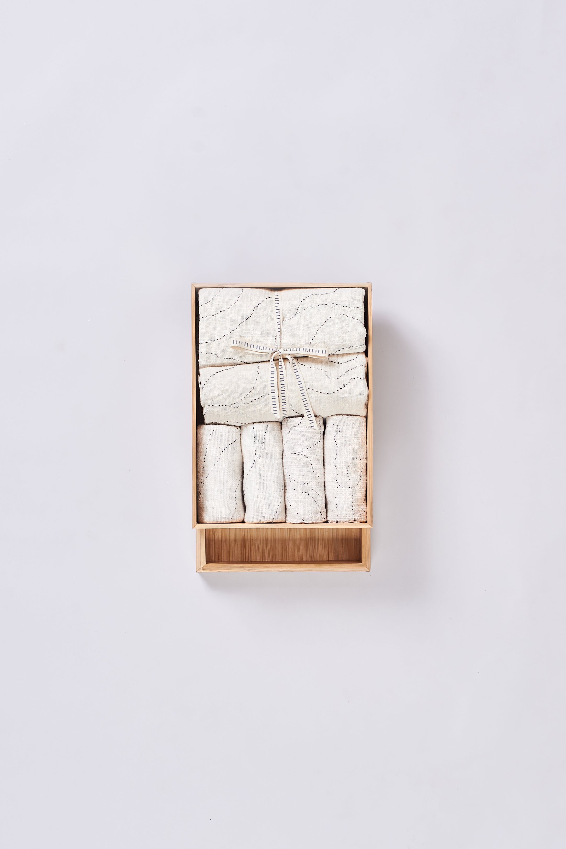 Set of folded towels in a wooden box on a grey background