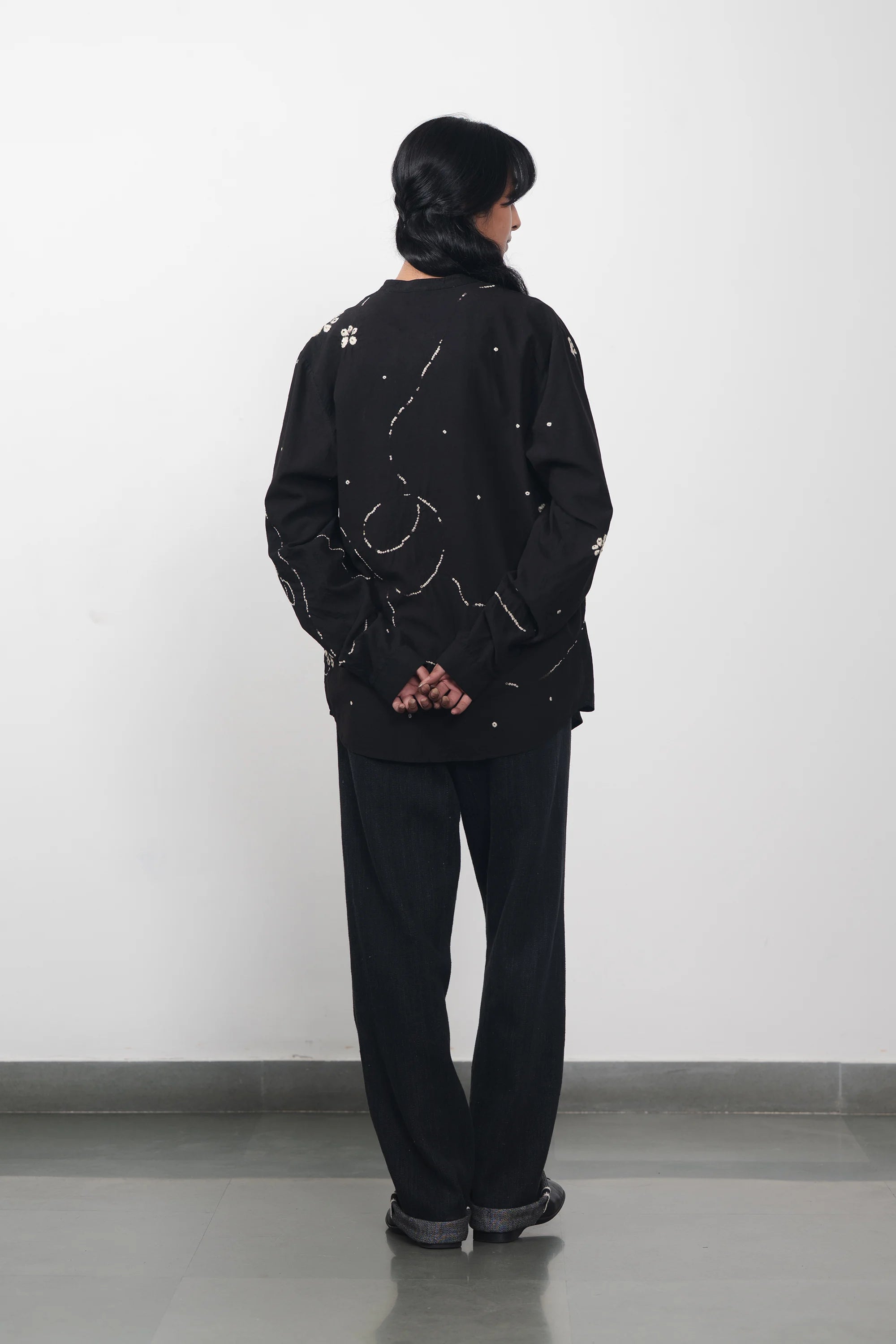 A back shot of a woman wearing black bandhani shirt