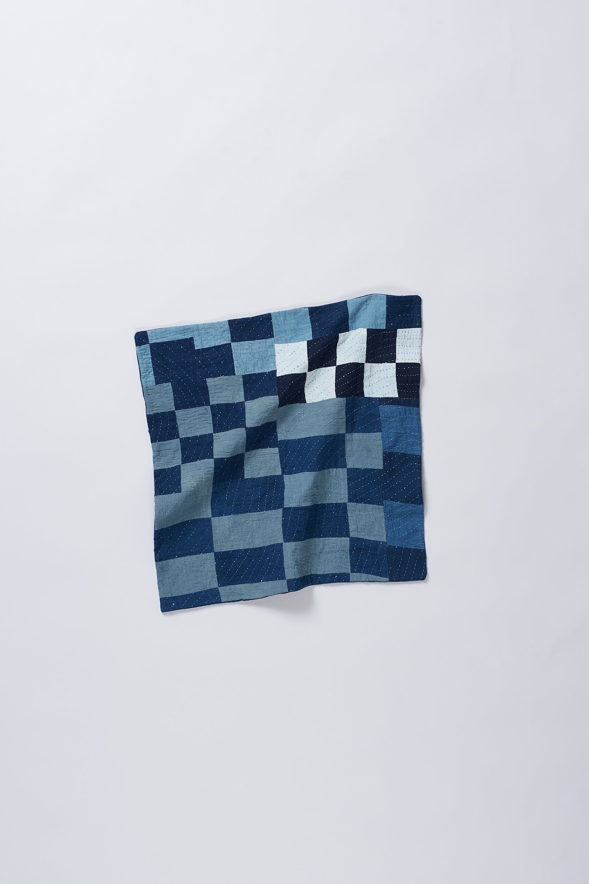 Patchwork indigo cushion on a light grey background