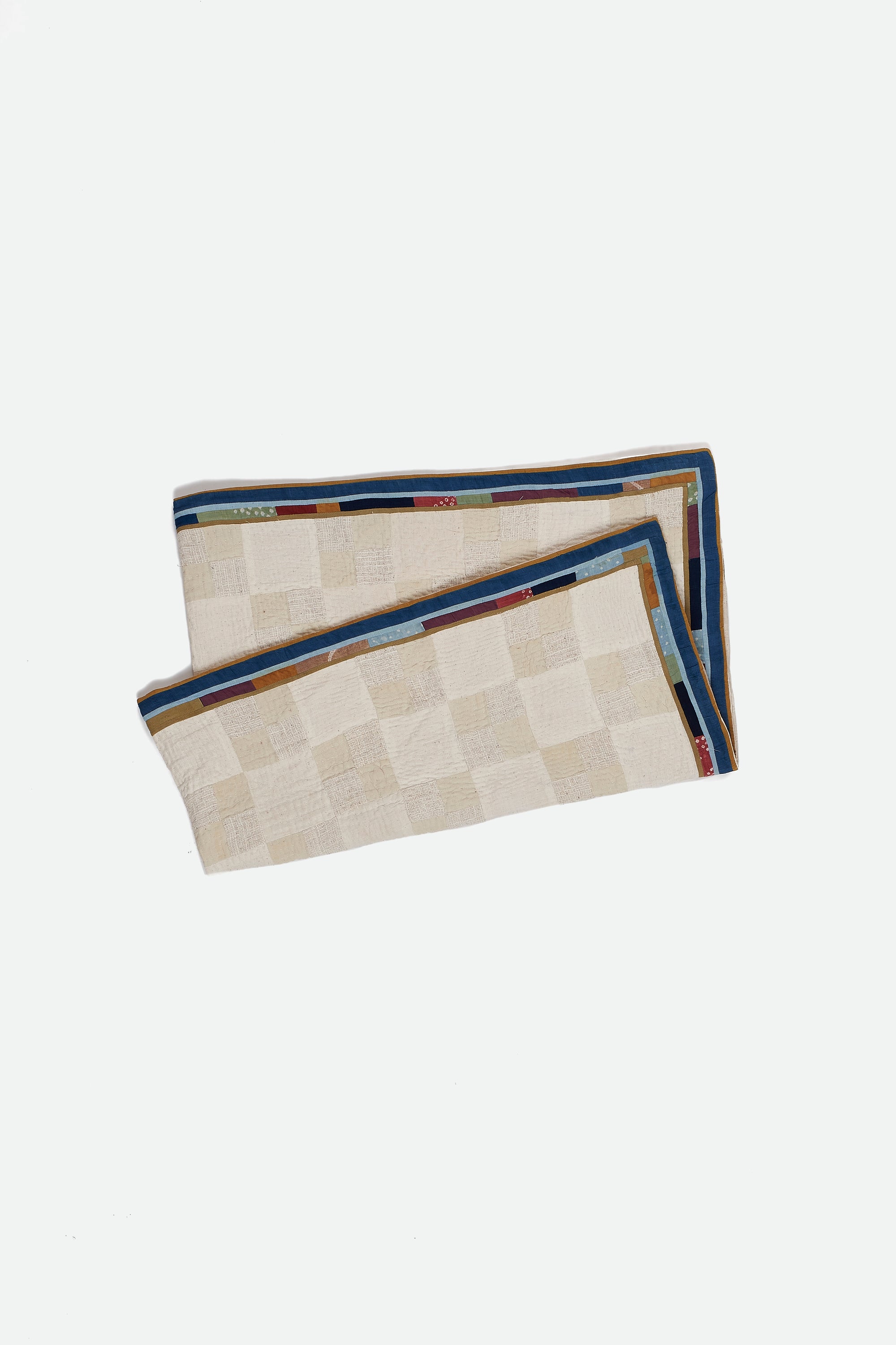 Ecru quilt with geometric pattern on a white background