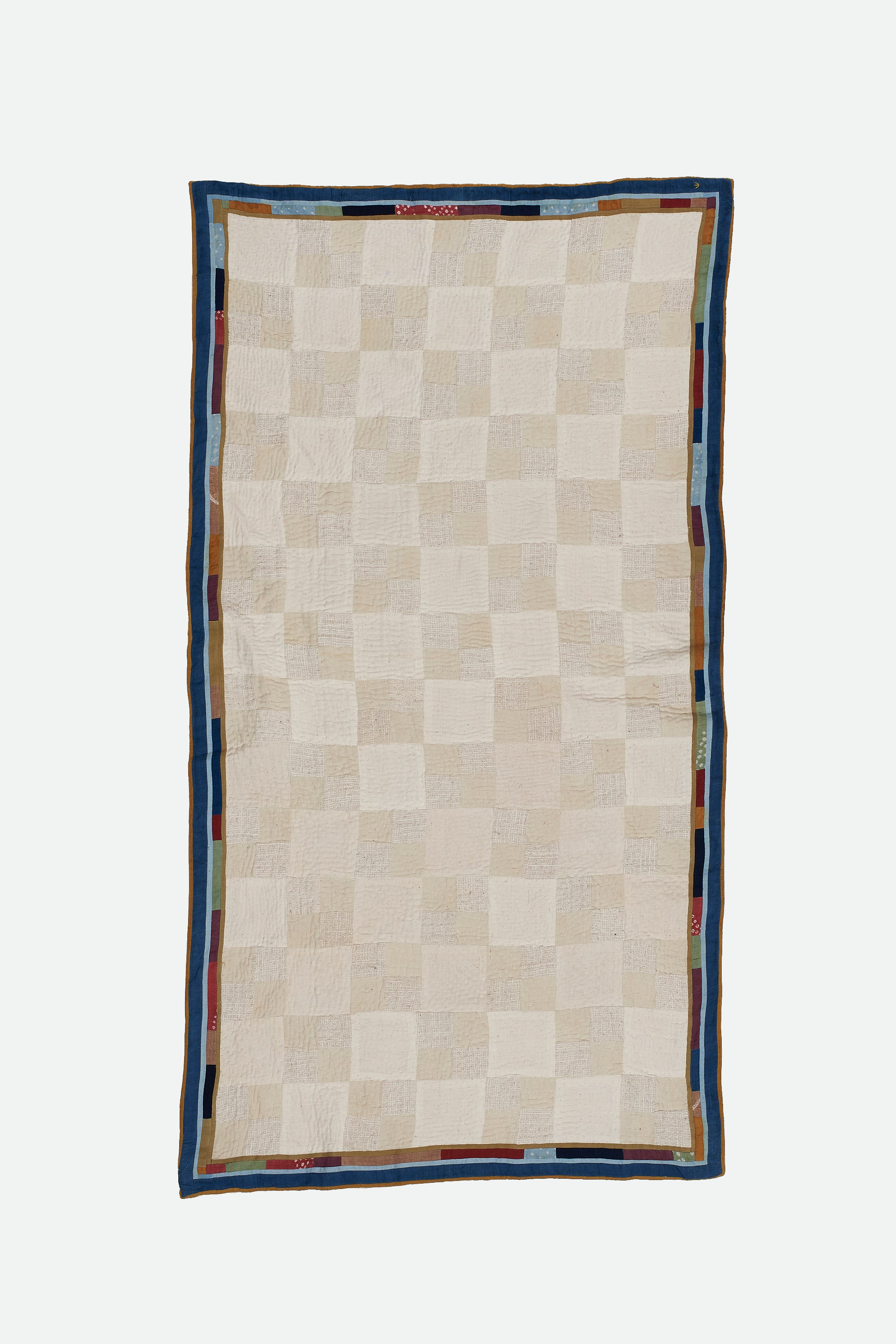 Ecru patchwork kantha quilt on a light grey background