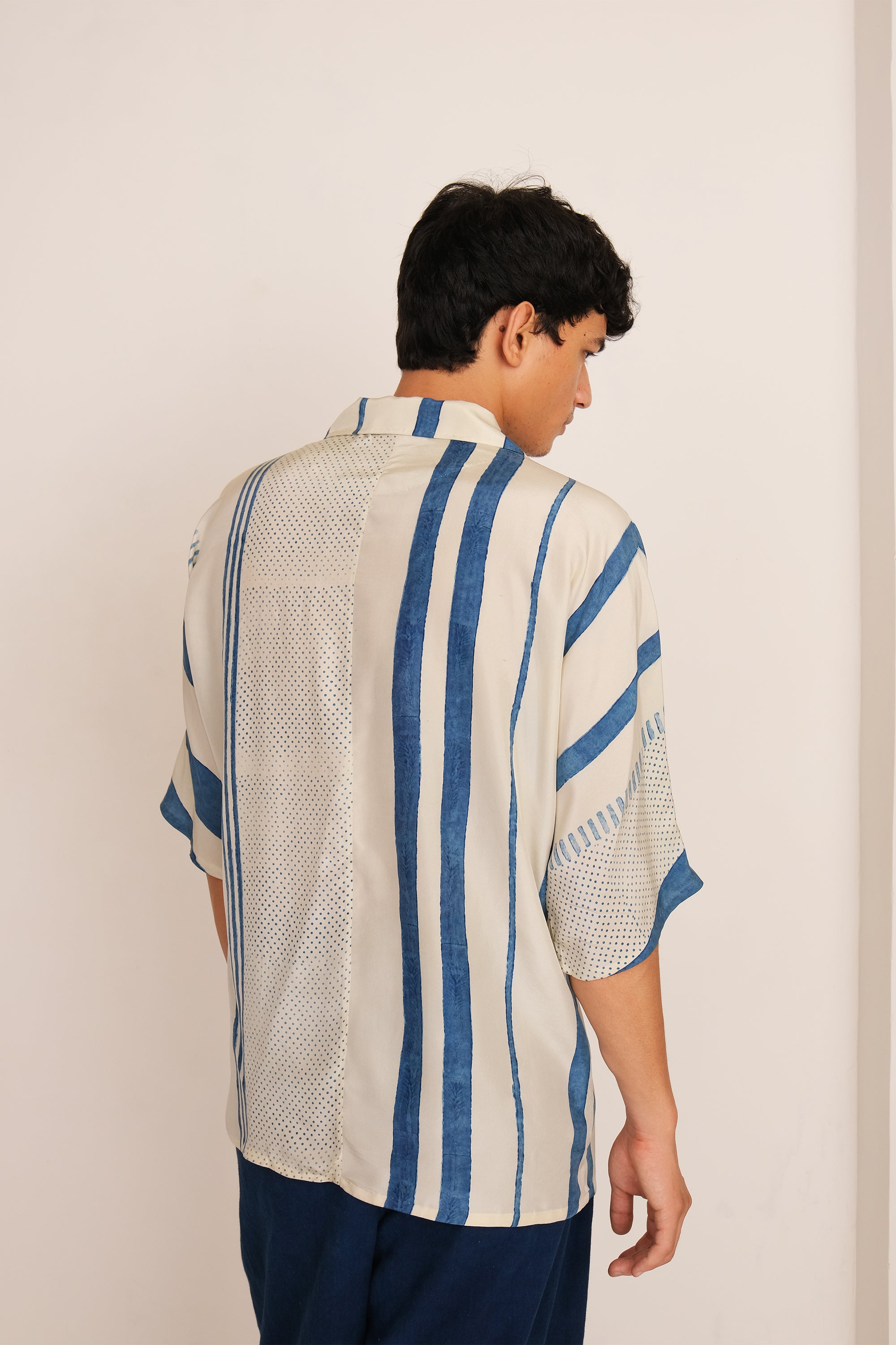  A back shot of a man wearing ecru shirt
