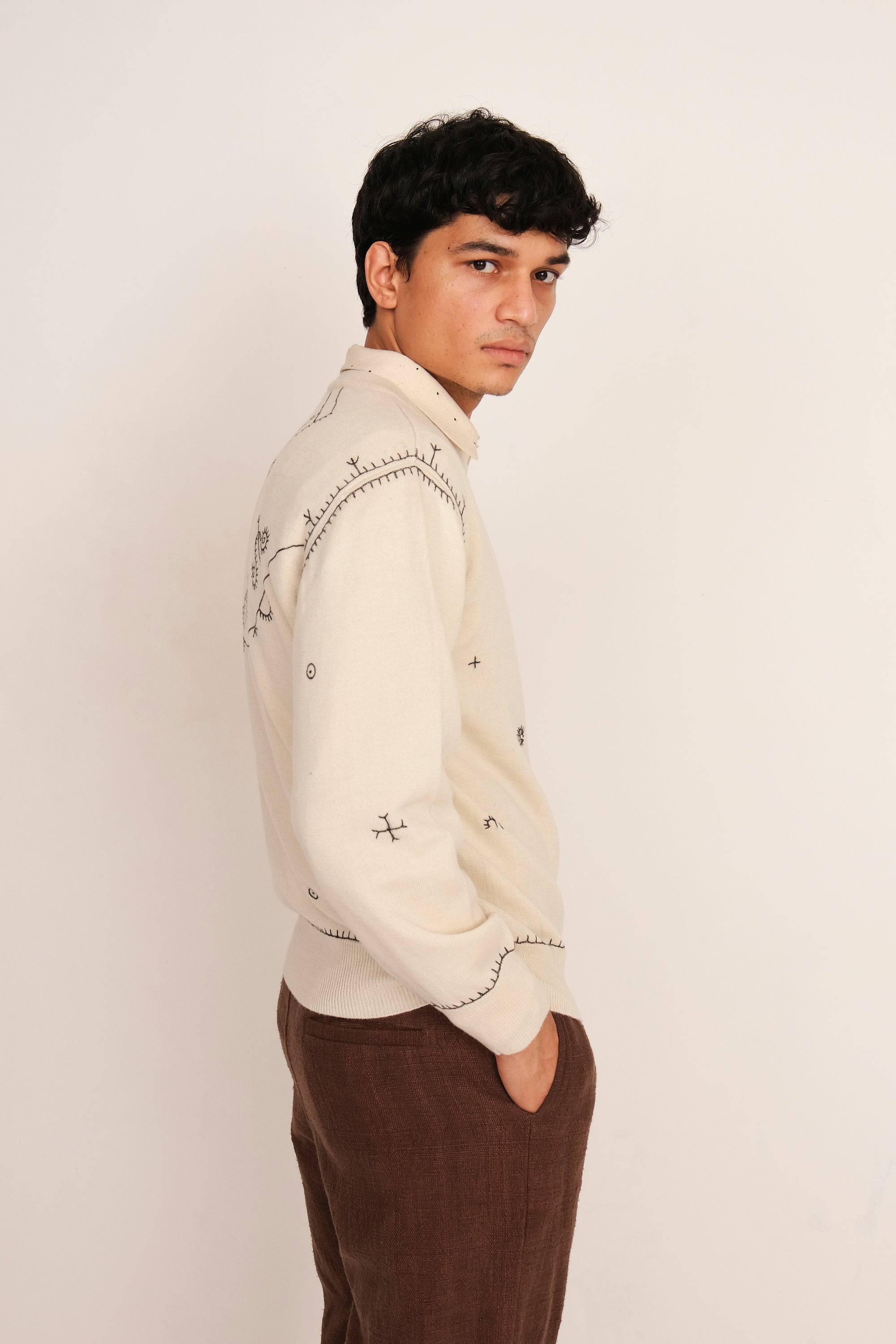 A side shot of a man wearing ecru sweatshirt shirt