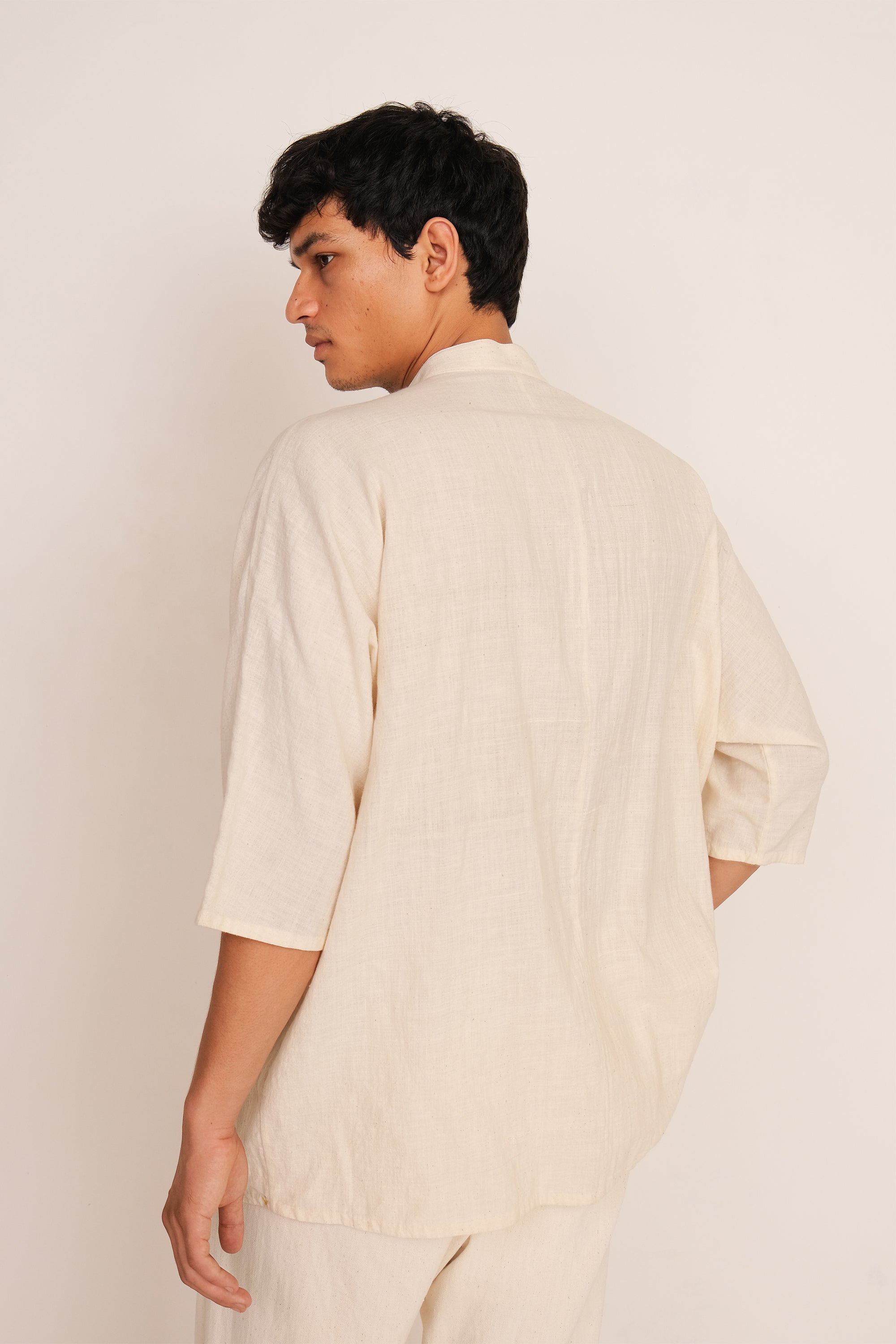 A back shot of a man wearing ecru cotton shirt