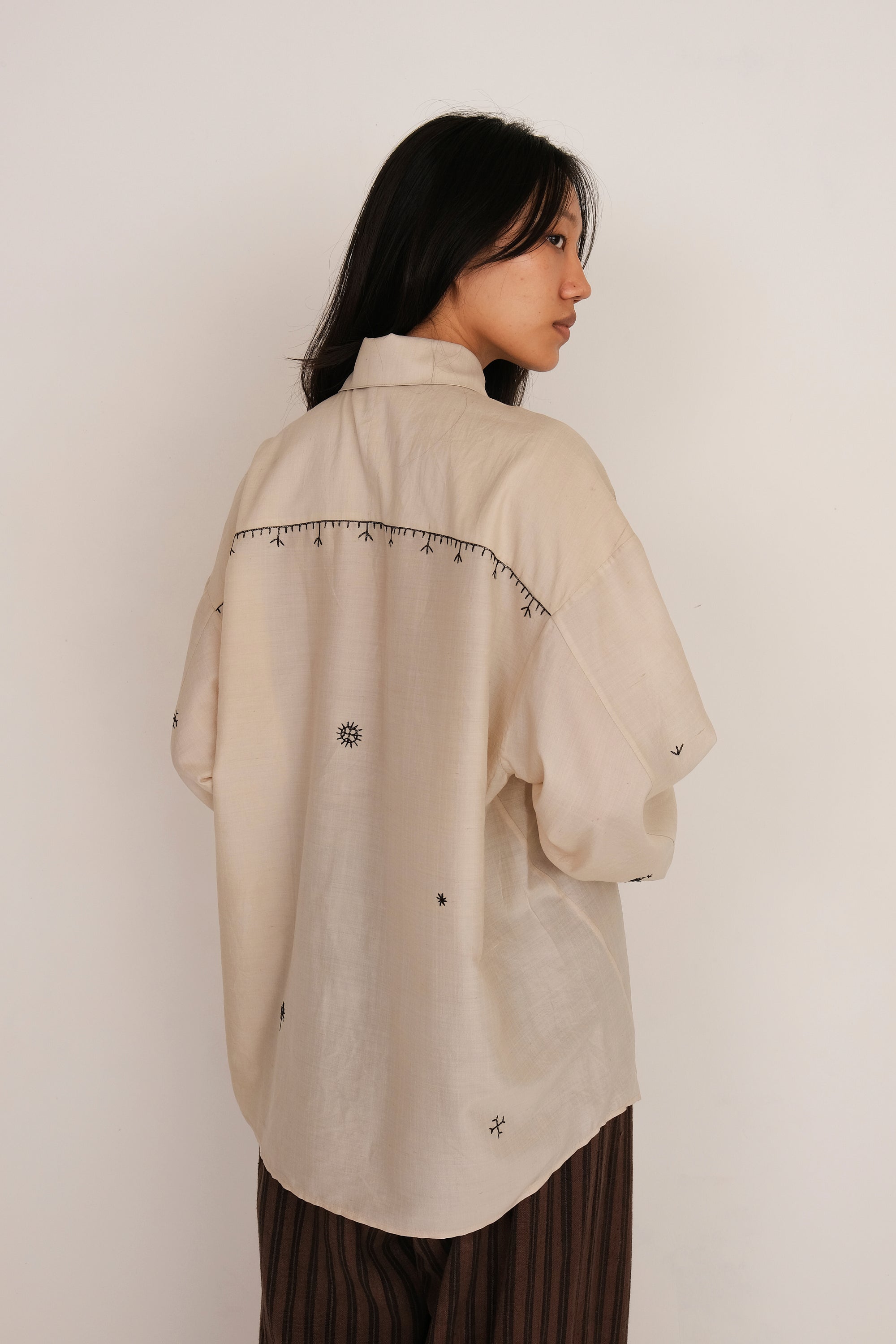A back shot of a woman wearing ecru shirt