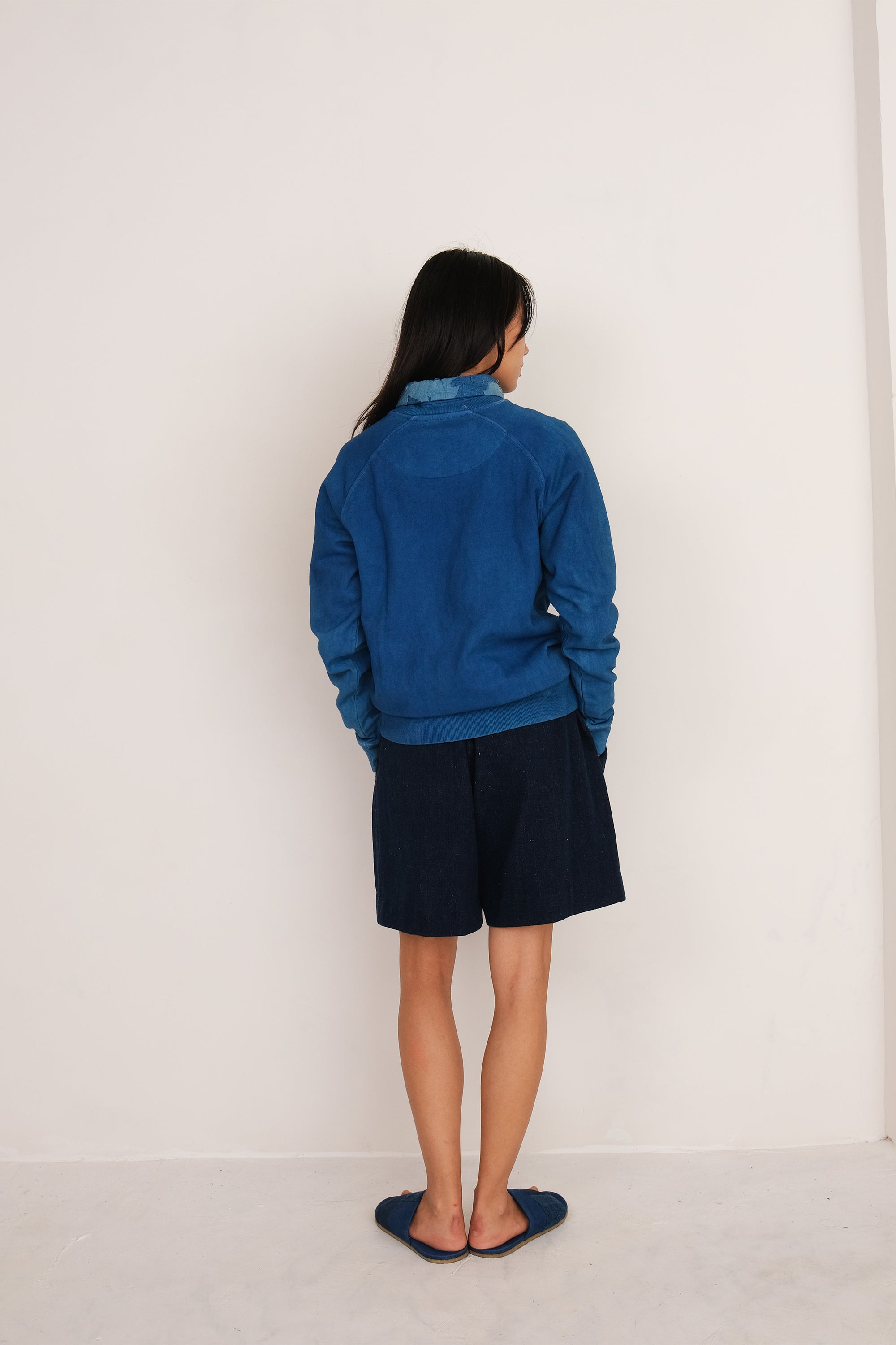 A back shot of a woman wearing indigo cotton sweatshirt
