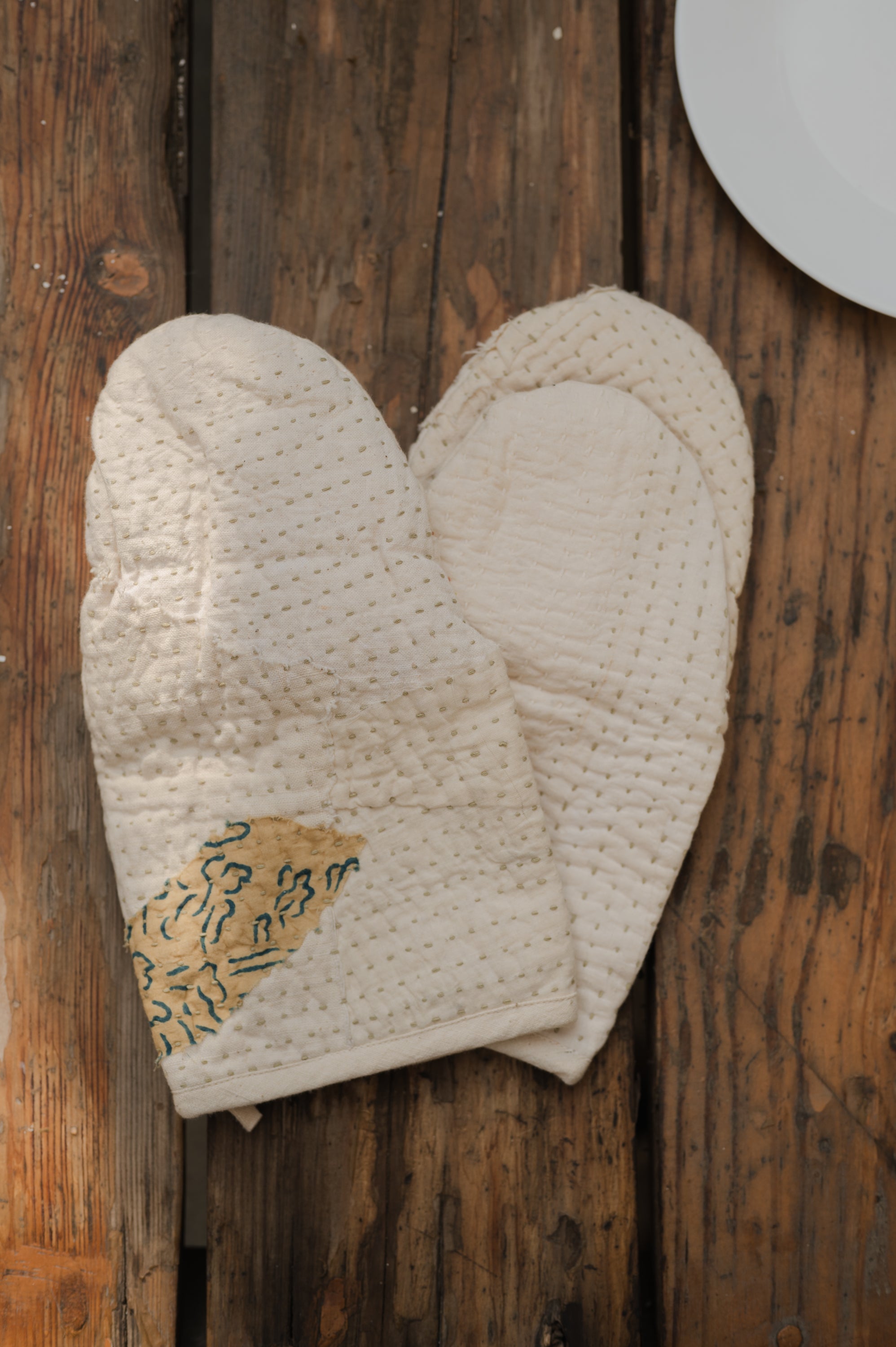 Pair of textured oven mitts on a wooden surface