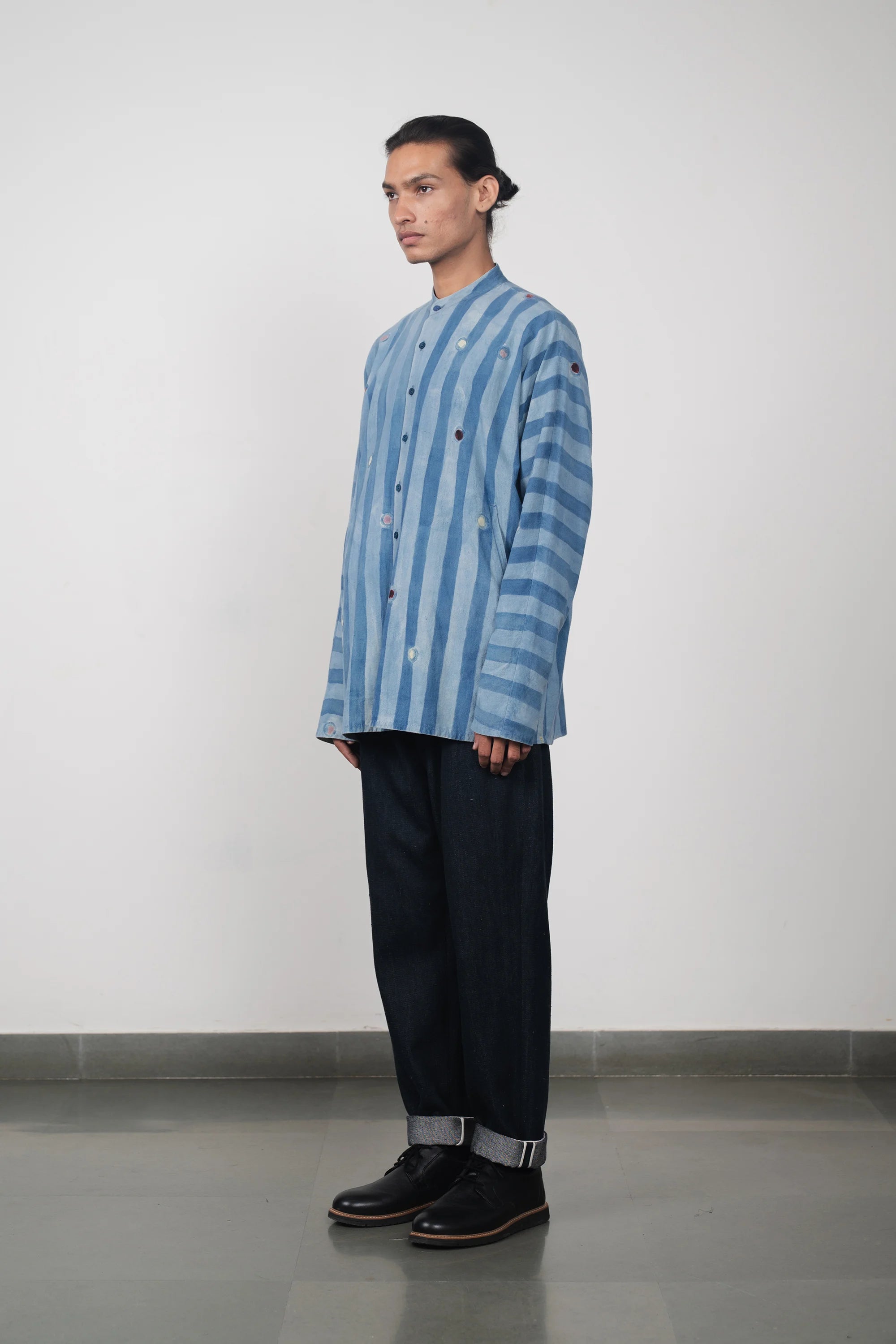 A side shot of a man wearing light indigo shirt