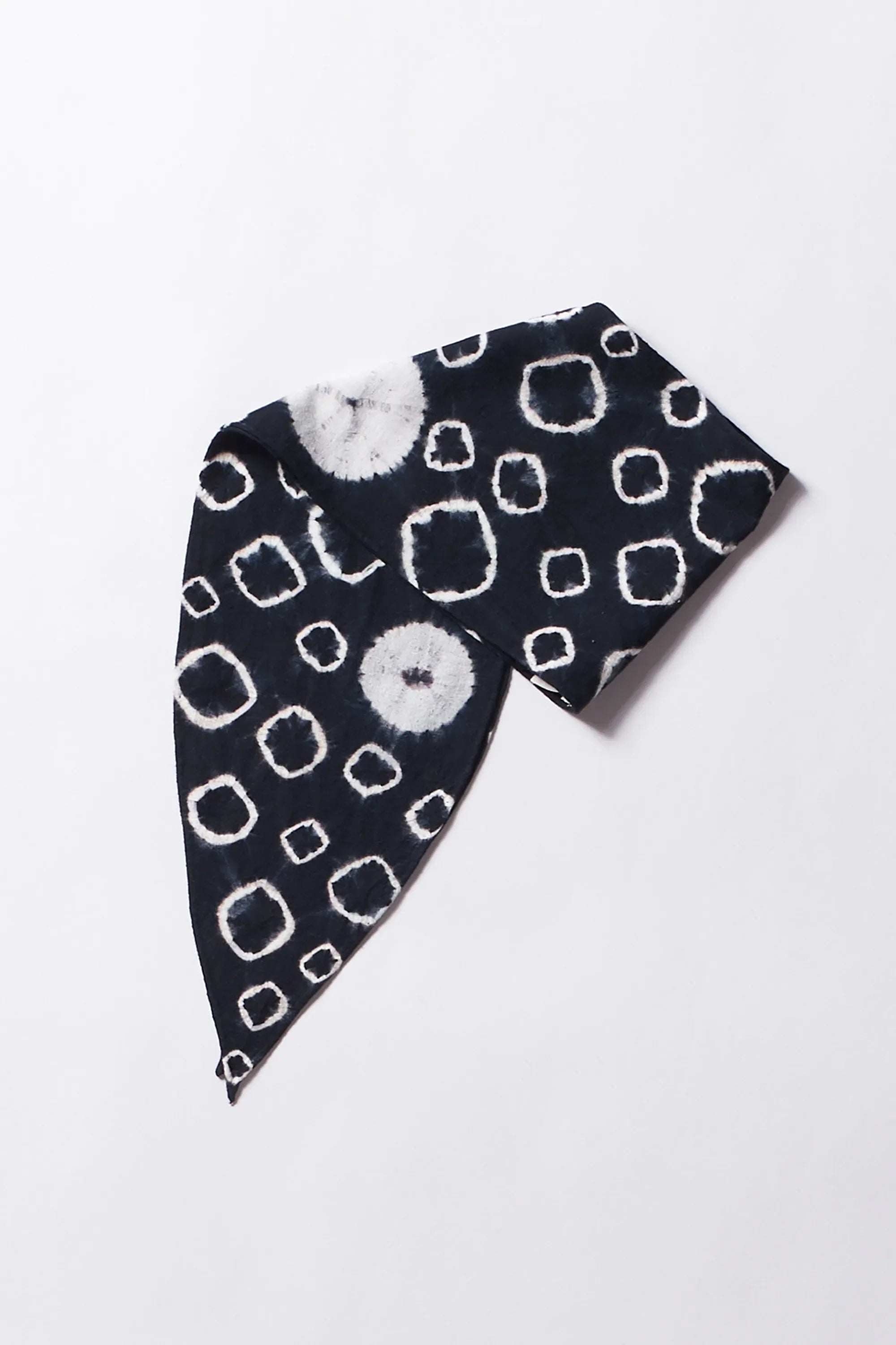 Black and white patterned knitted bandana on a light grey background