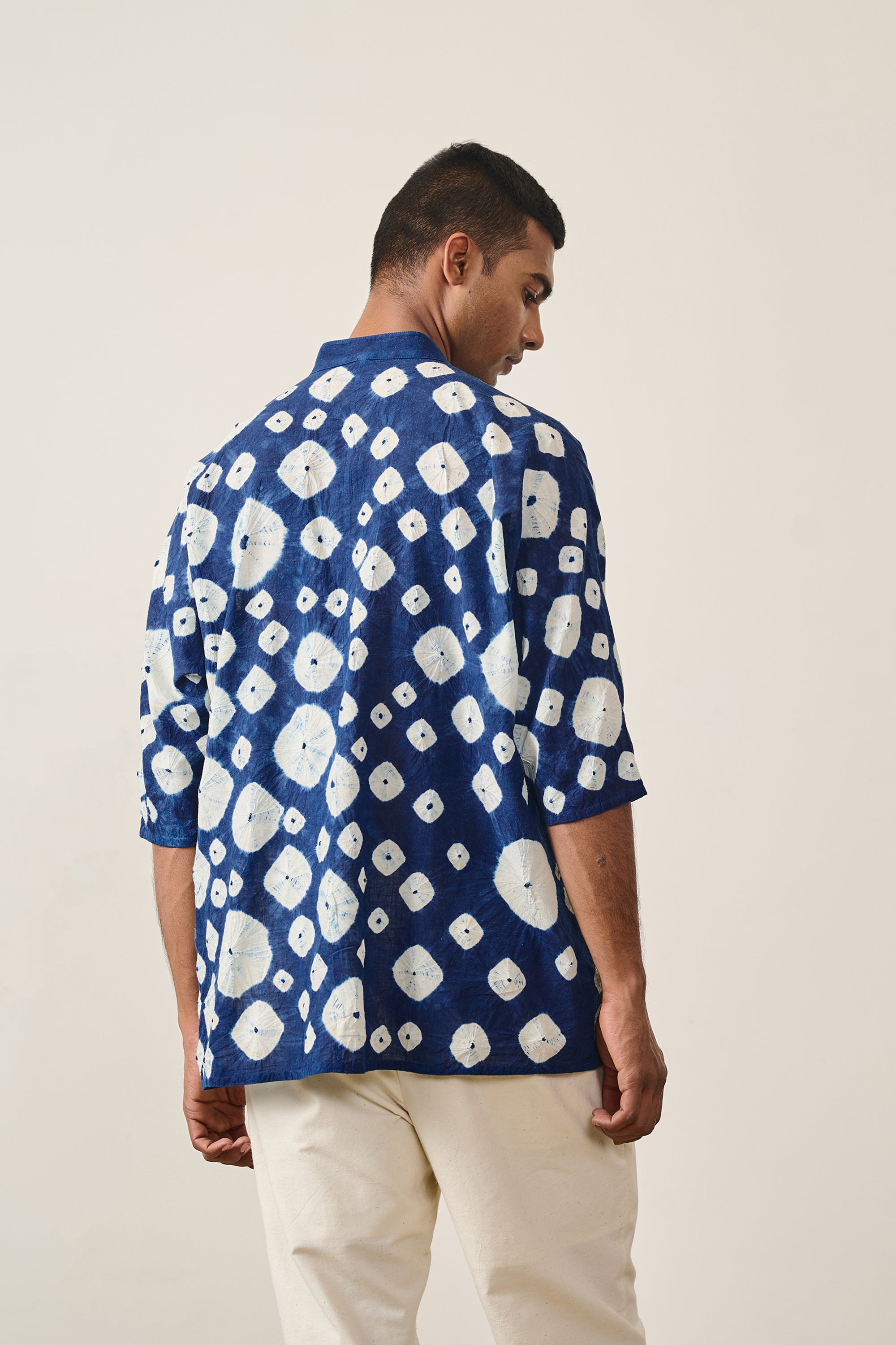 A back shot of a man wearing medium indigo shirt
