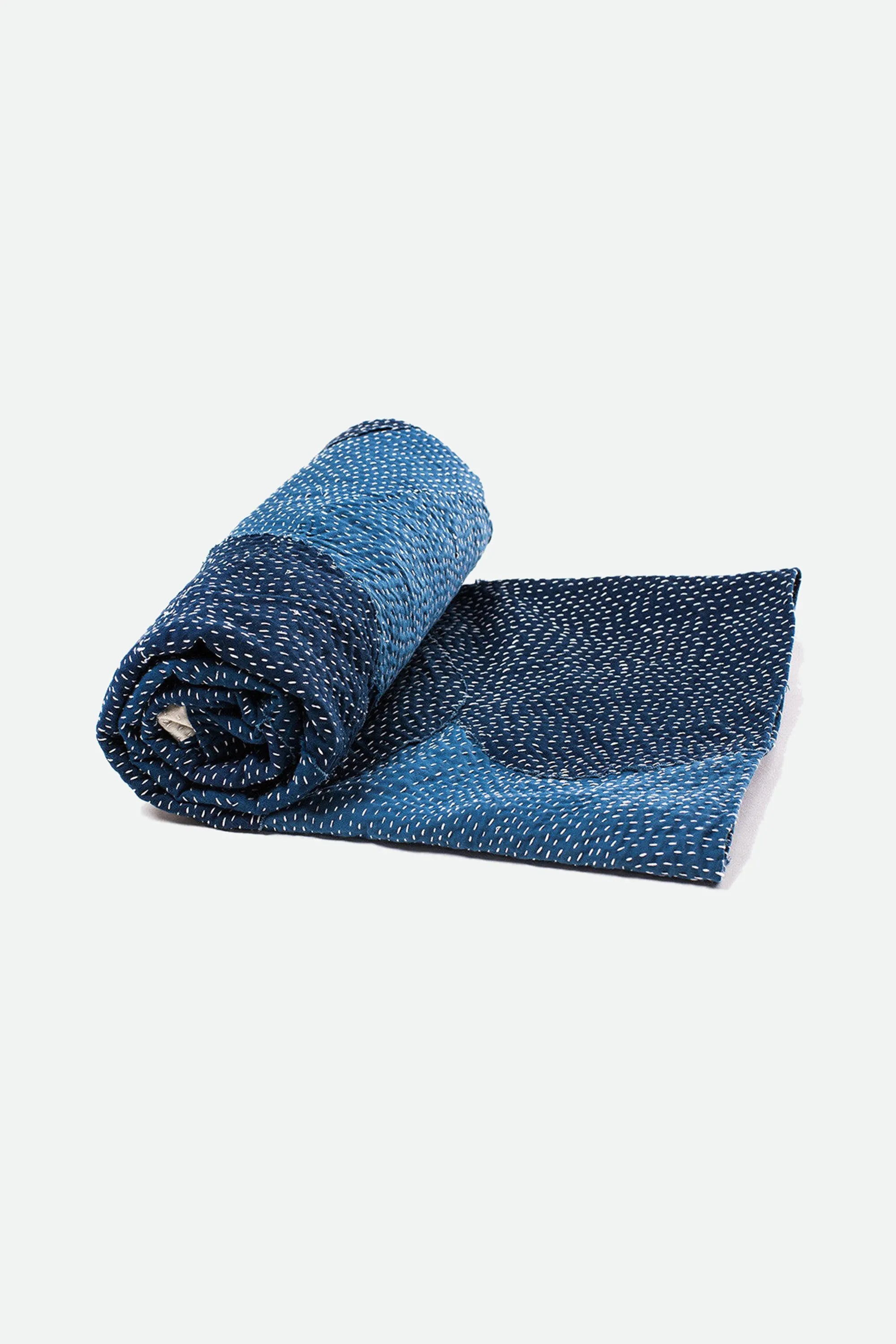 Rolled-up indigo textured quilt on a grey background