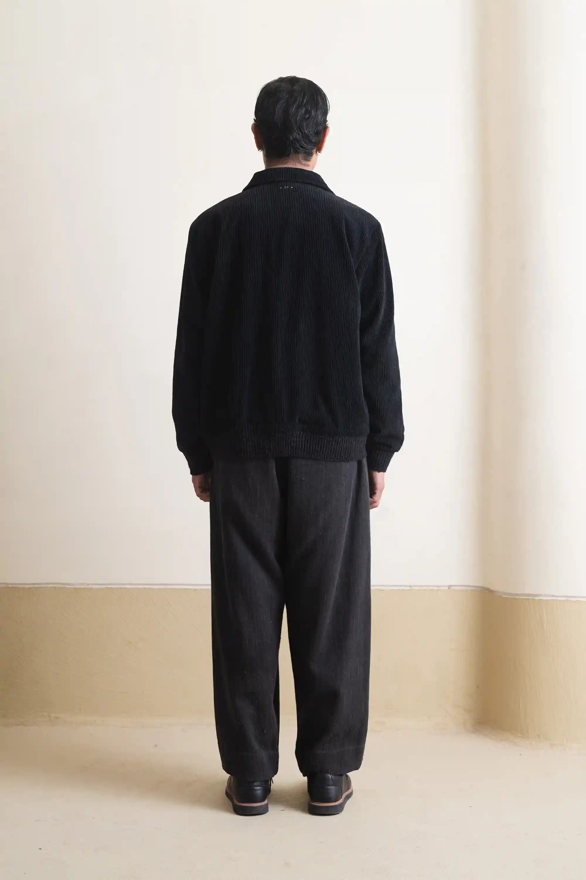 A back shot of a man wearing black cotton jacket in black