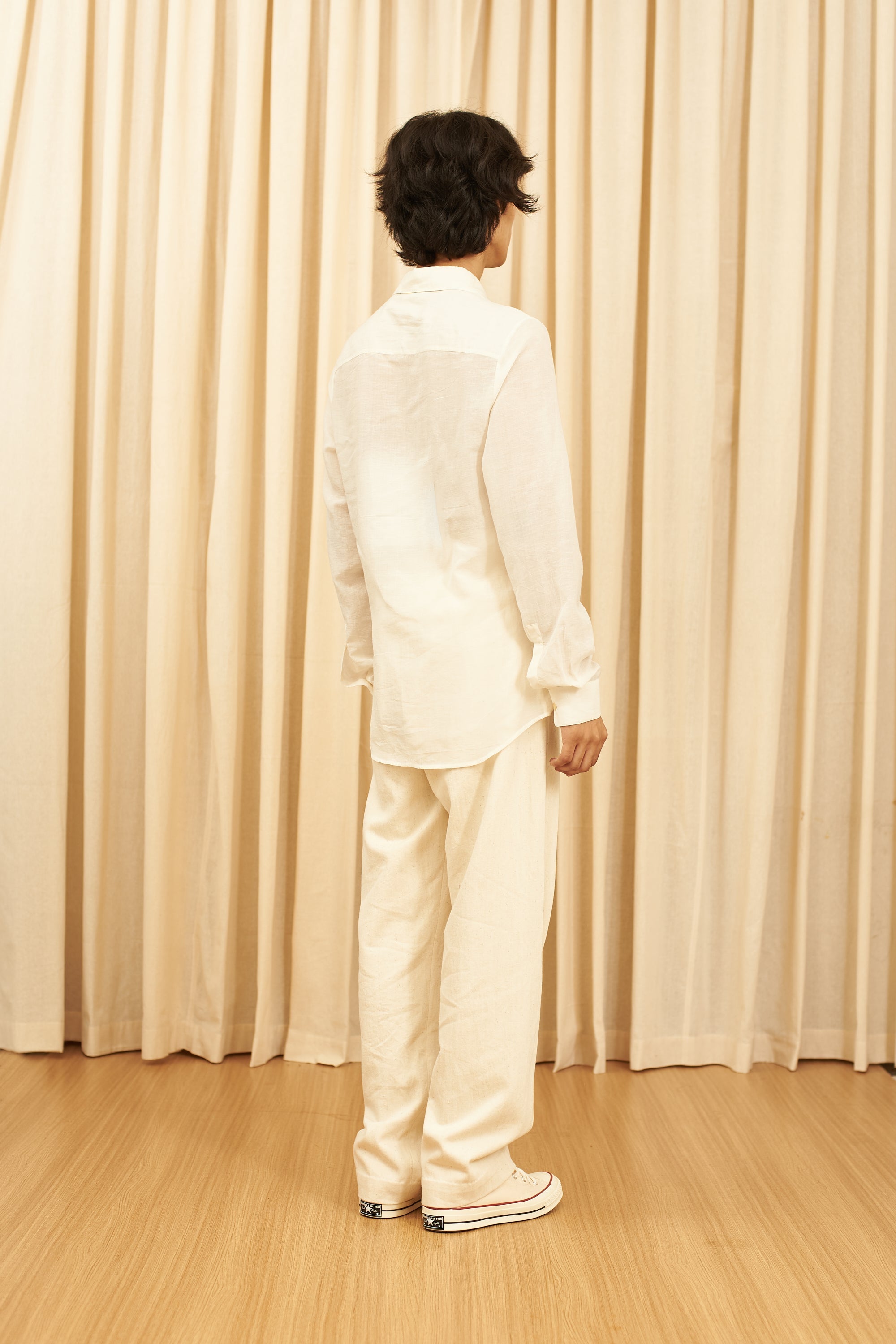 A back shot of a man wearing ecru shirt