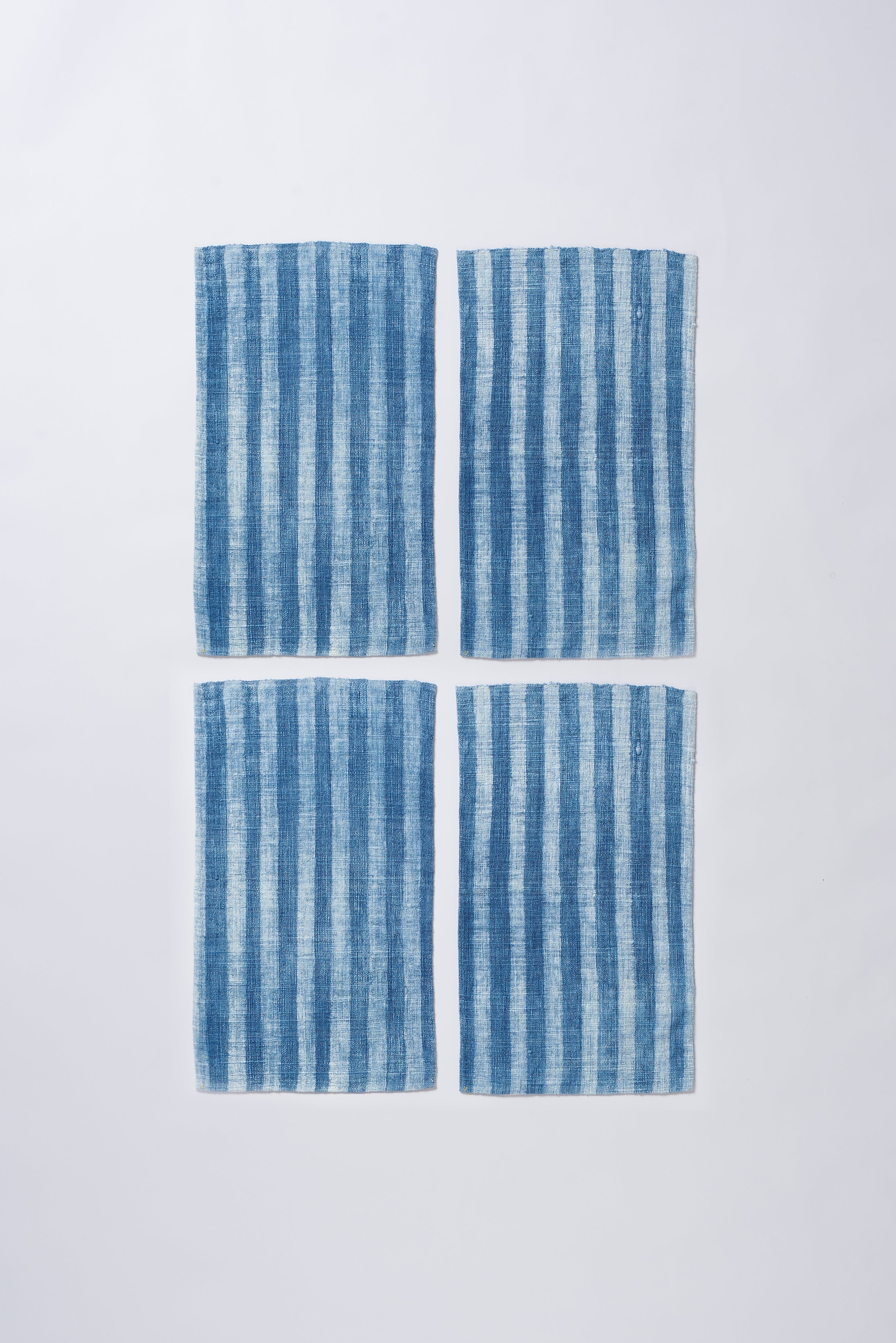 Four indigo and white striped small towel a grey background