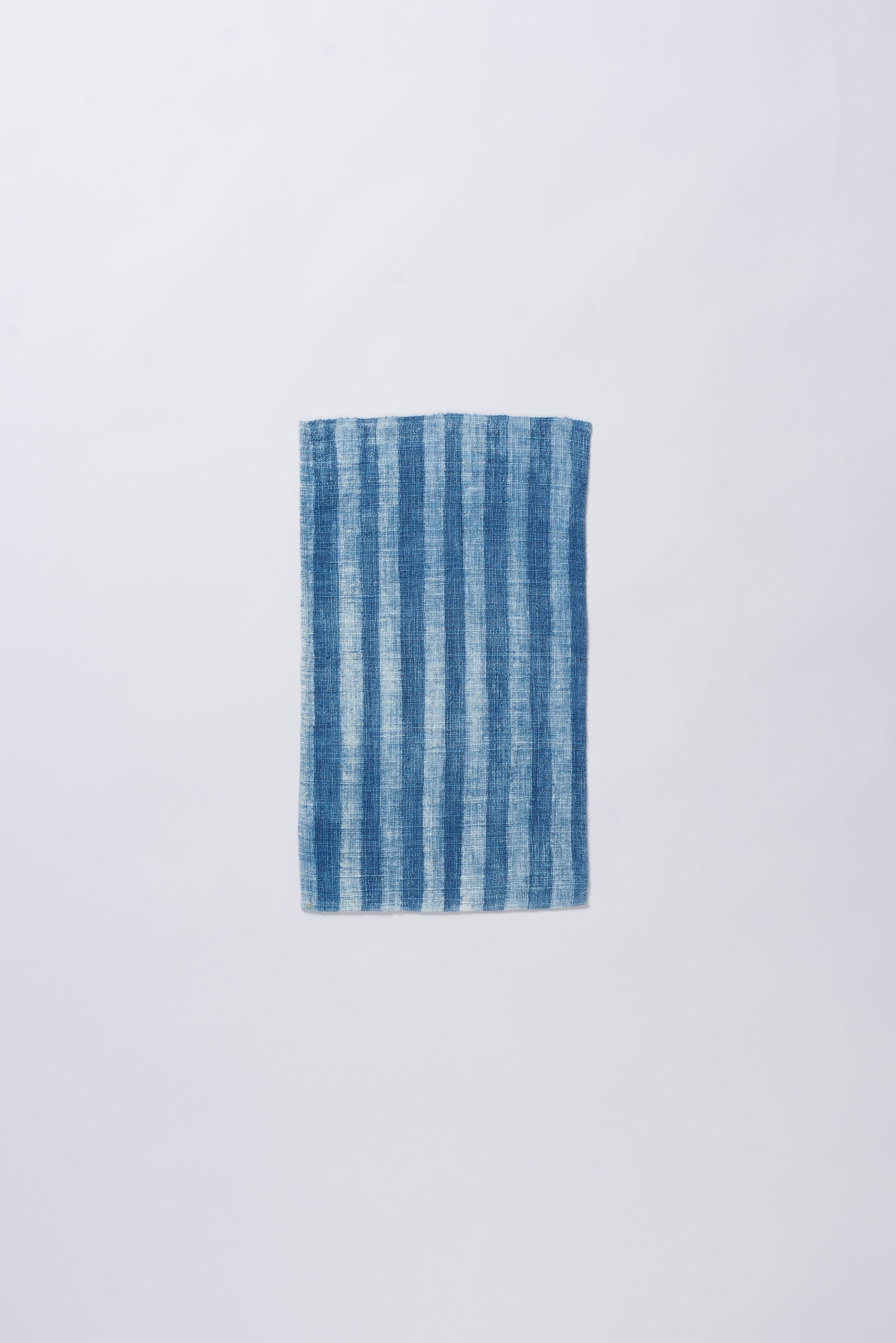 Indigo and white striped small towel a grey background