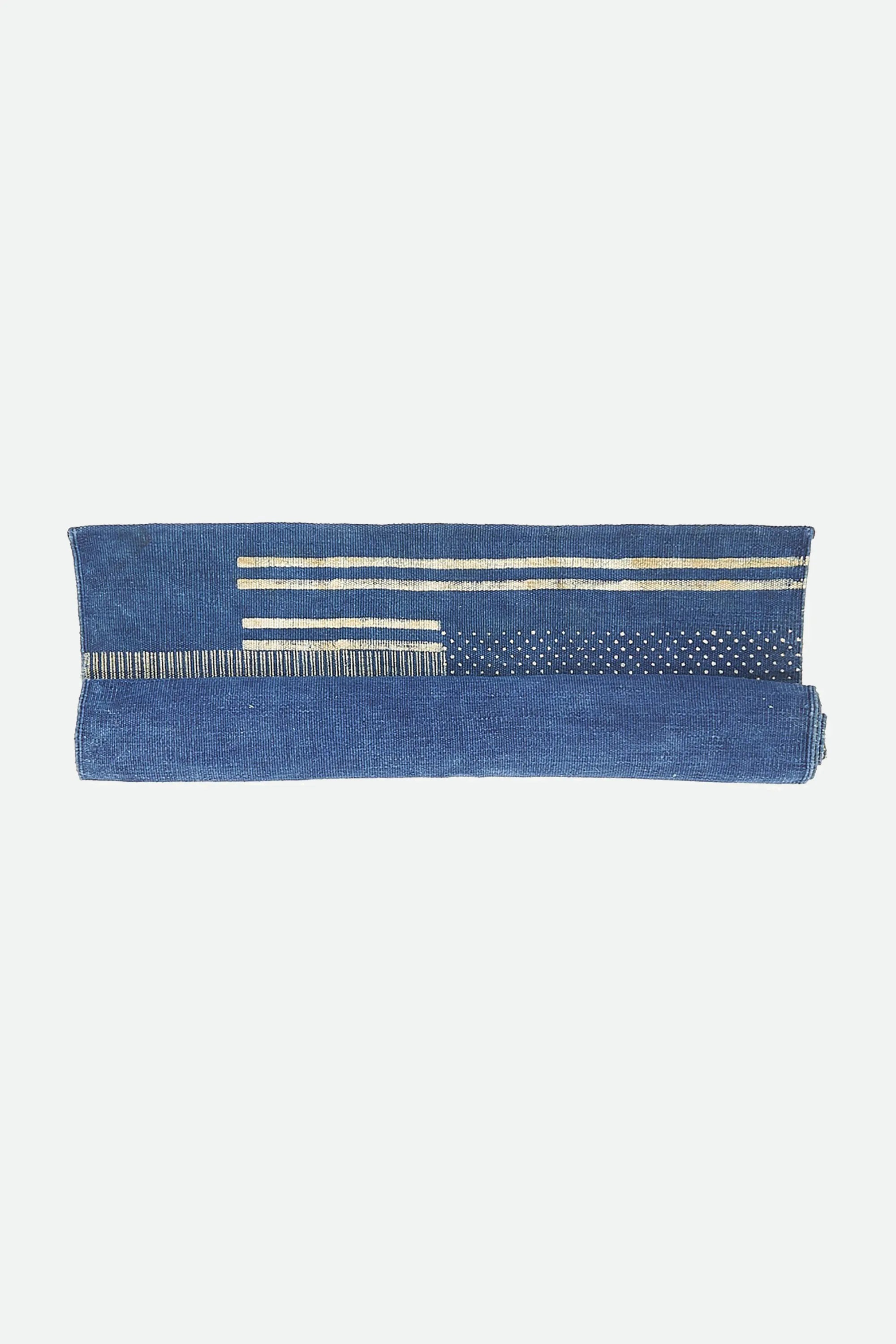 Indigo block print rug roll on a light grey background