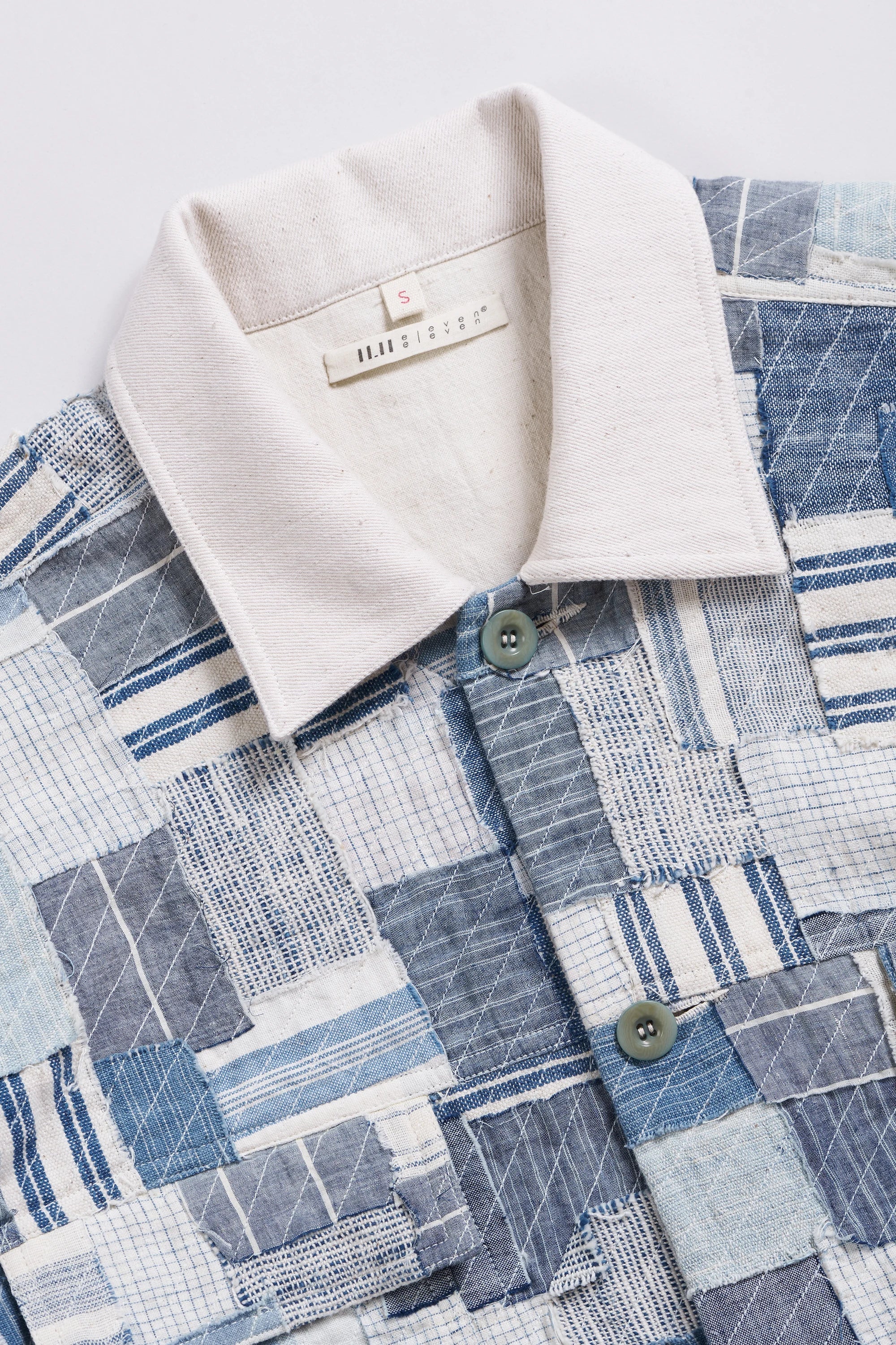 Close-up of a fabric with a patchwork and a beige collar and buttons