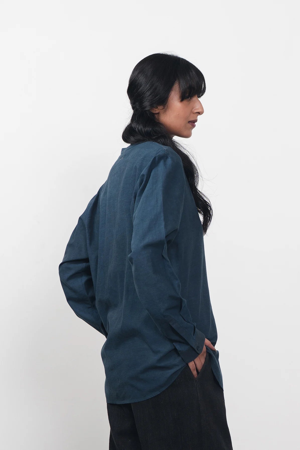 A side shot of a woman wearing estate blue shirt